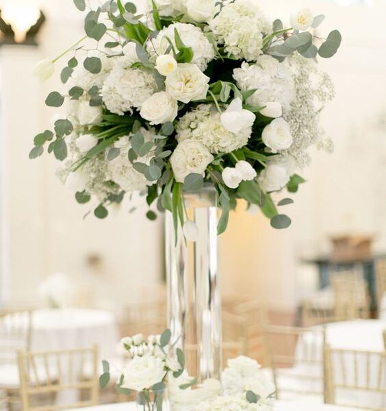 Aranžman u visokoj staklenoj posudi u kombinaciji sa malim posudama i aranžmanima